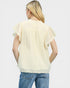 Woman wearing a light yellow blouse with ruffled sleeves and blue jeans on a white background