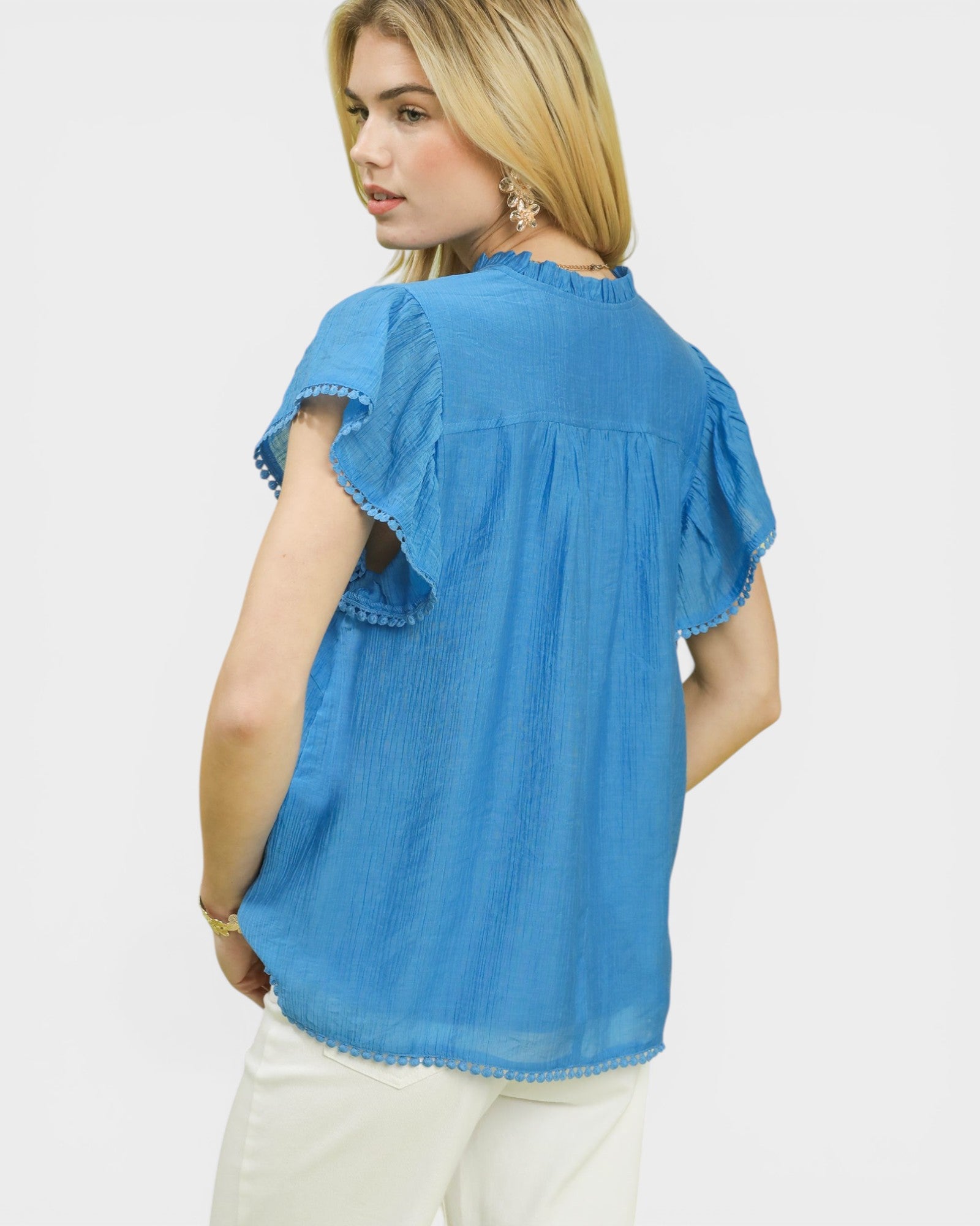Woman wearing a blue blouse with ruffled sleeves on a white background