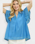 Woman wearing a blue blouse with ruffled sleeves on a white background