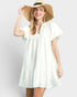 Woman wearing a white dress and straw hat on a plain background