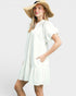 Woman wearing a white dress and wide-brimmed hat on a plain background