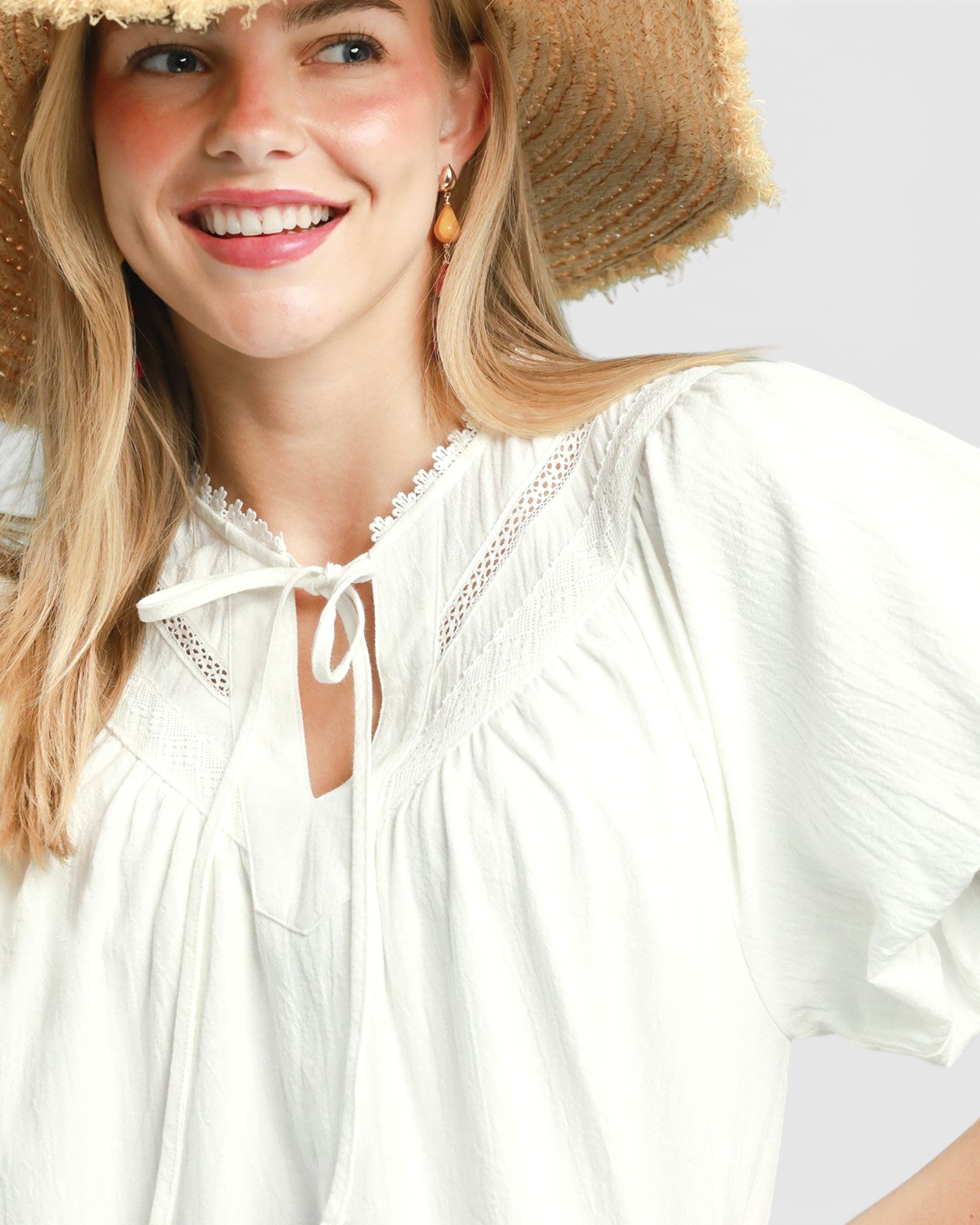 Woman wearing a white blouse and straw hat on a plain background