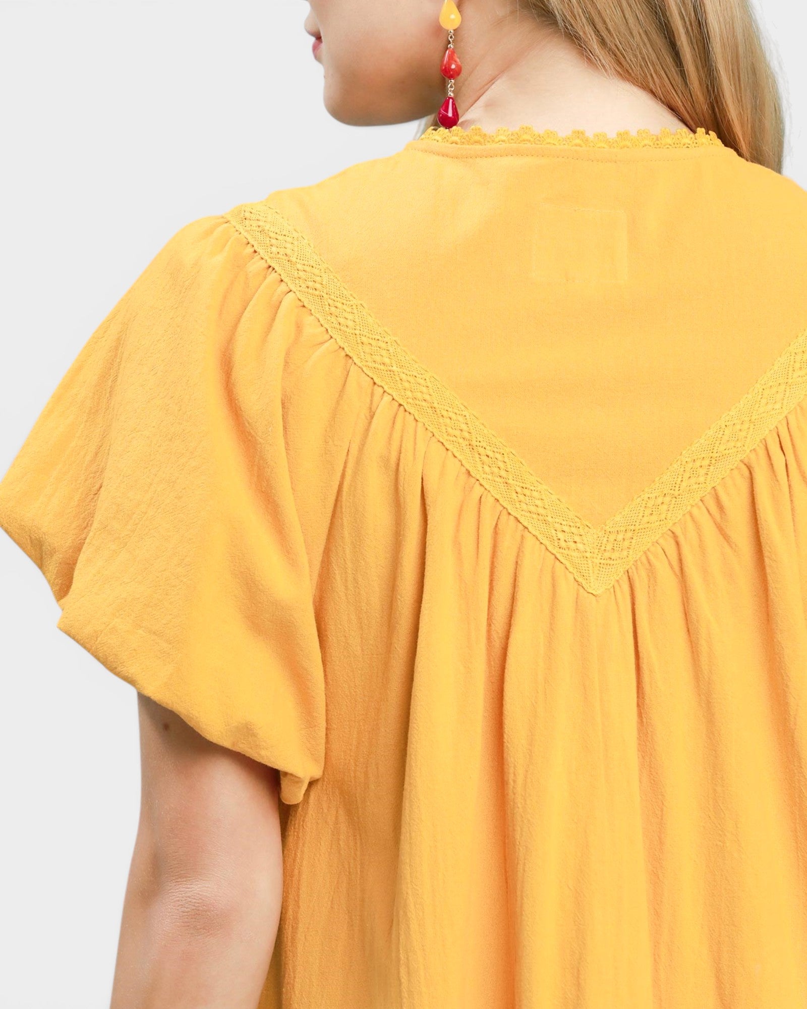 Yellow top with lace trim on a plain background
