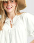 Woman wearing a white blouse and straw hat on a plain background