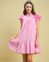 Woman wearing a pink dress with ruffled sleeves on a beige background
