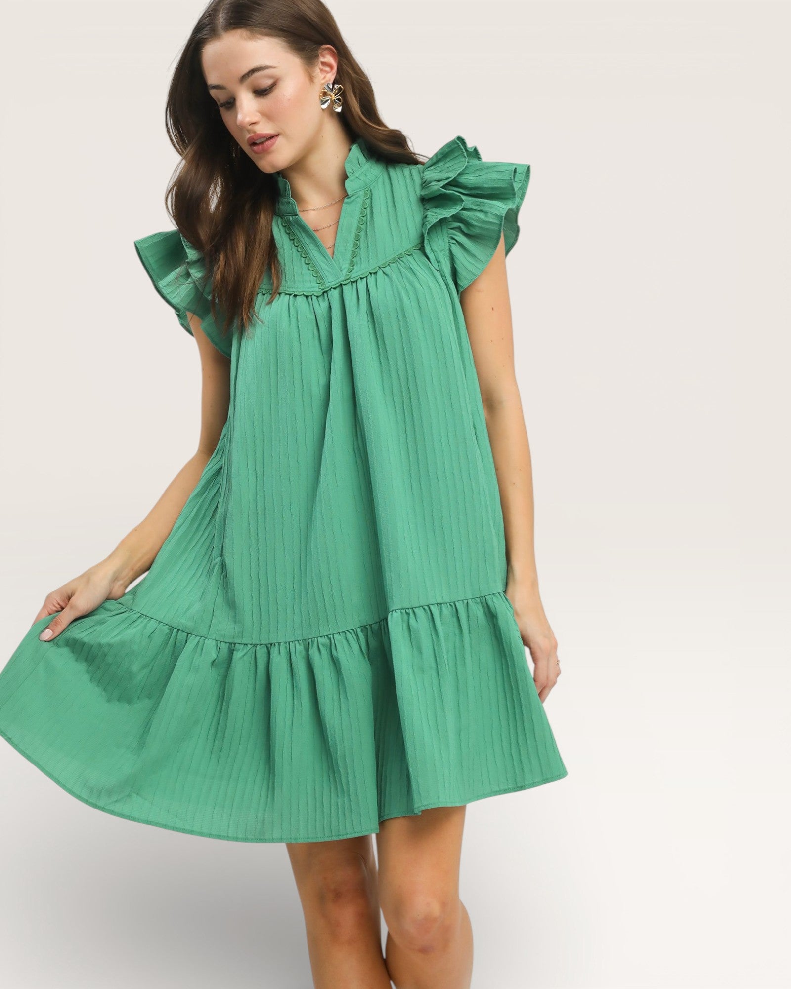 Woman wearing a green dress with ruffled details on a white background