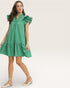 Woman wearing a green dress with ruffled details on a white background