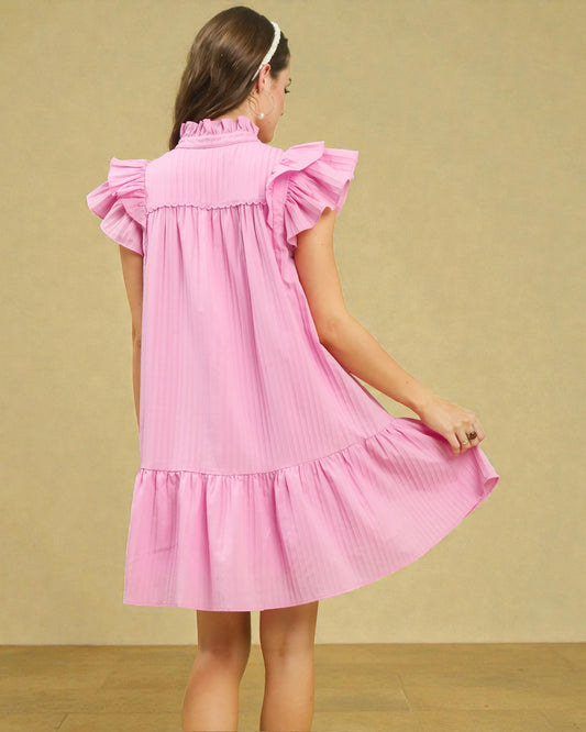 Pink dress with ruffled sleeves and bottom worn by a person on a beige background