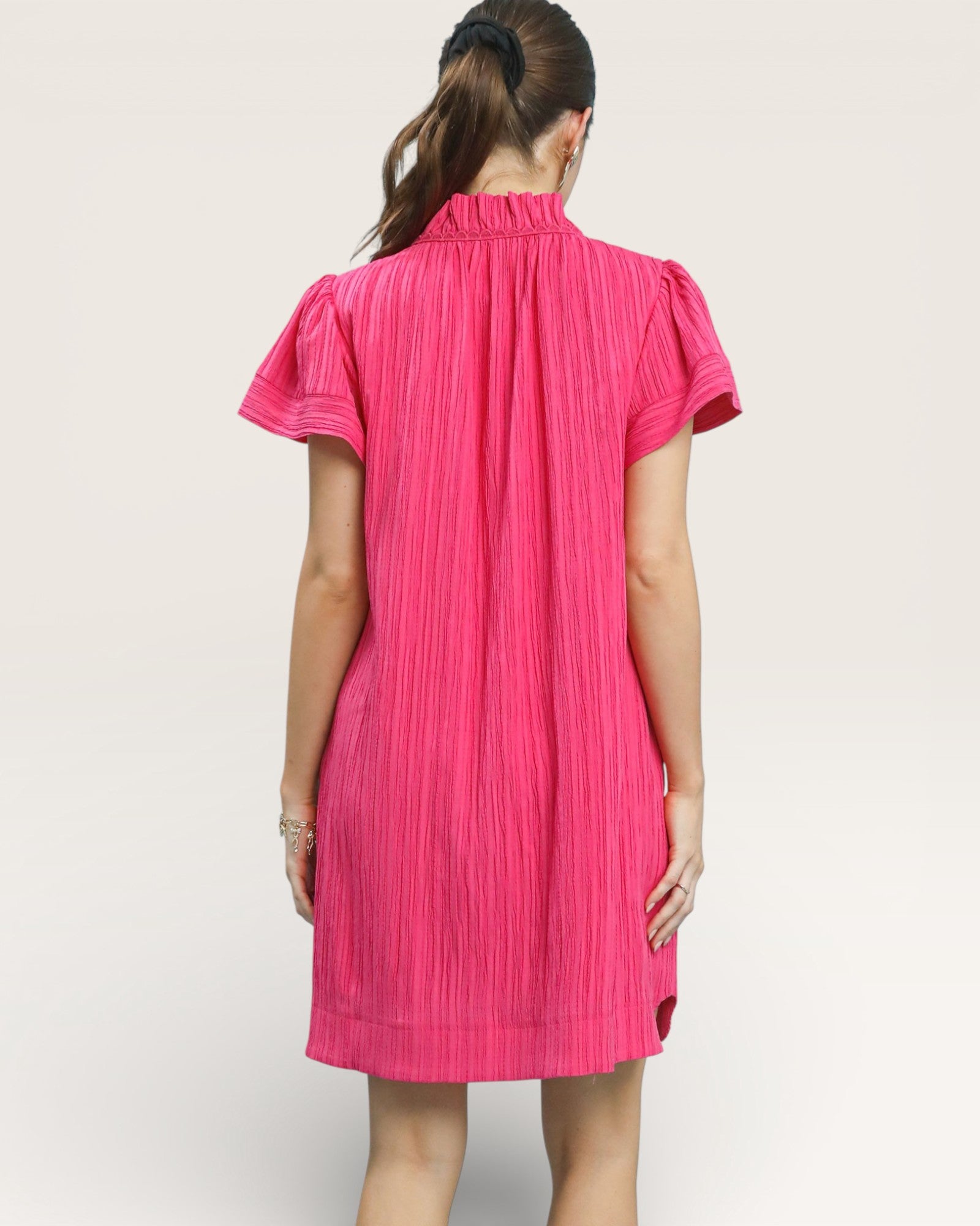 Person wearing a bright pink dress on a plain background