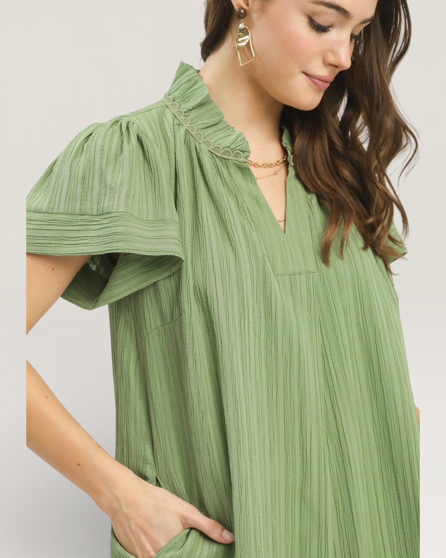 Woman wearing a green pleated dress with a plain background