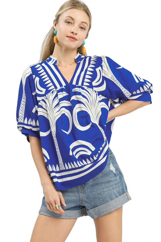 Woman wearing a blue and white patterned blouse with denim shorts on a white background