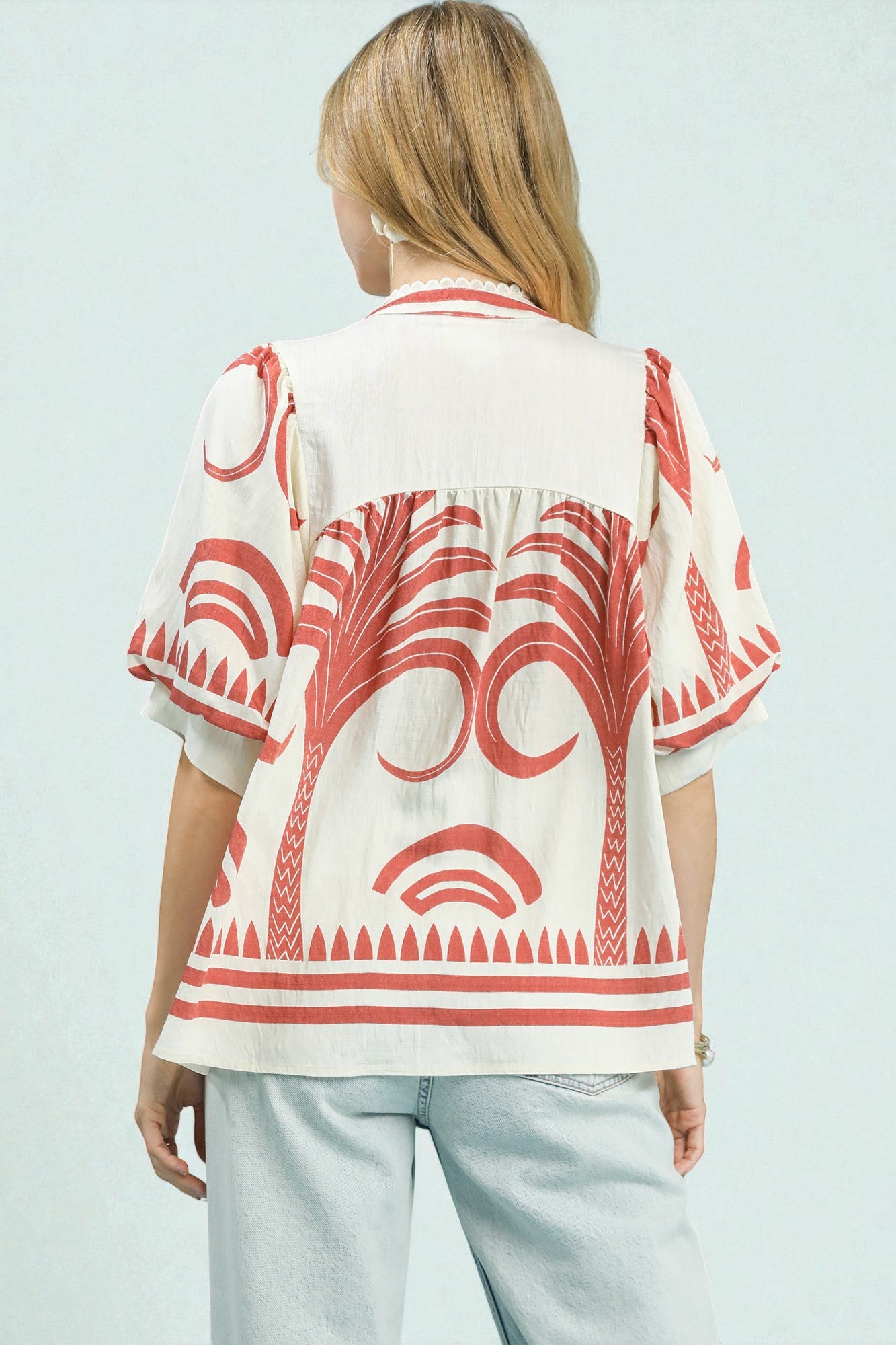 Woman wearing a red and white patterned blouse on a light blue background