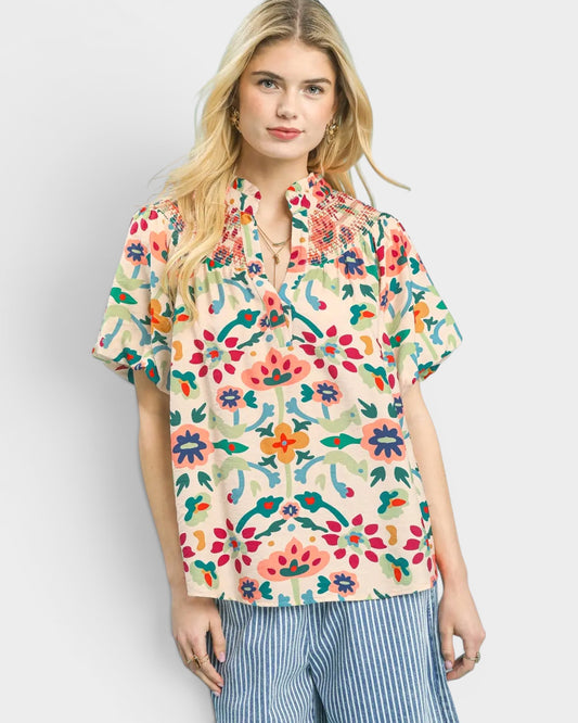 Woman wearing a colorful floral blouse against a plain background
