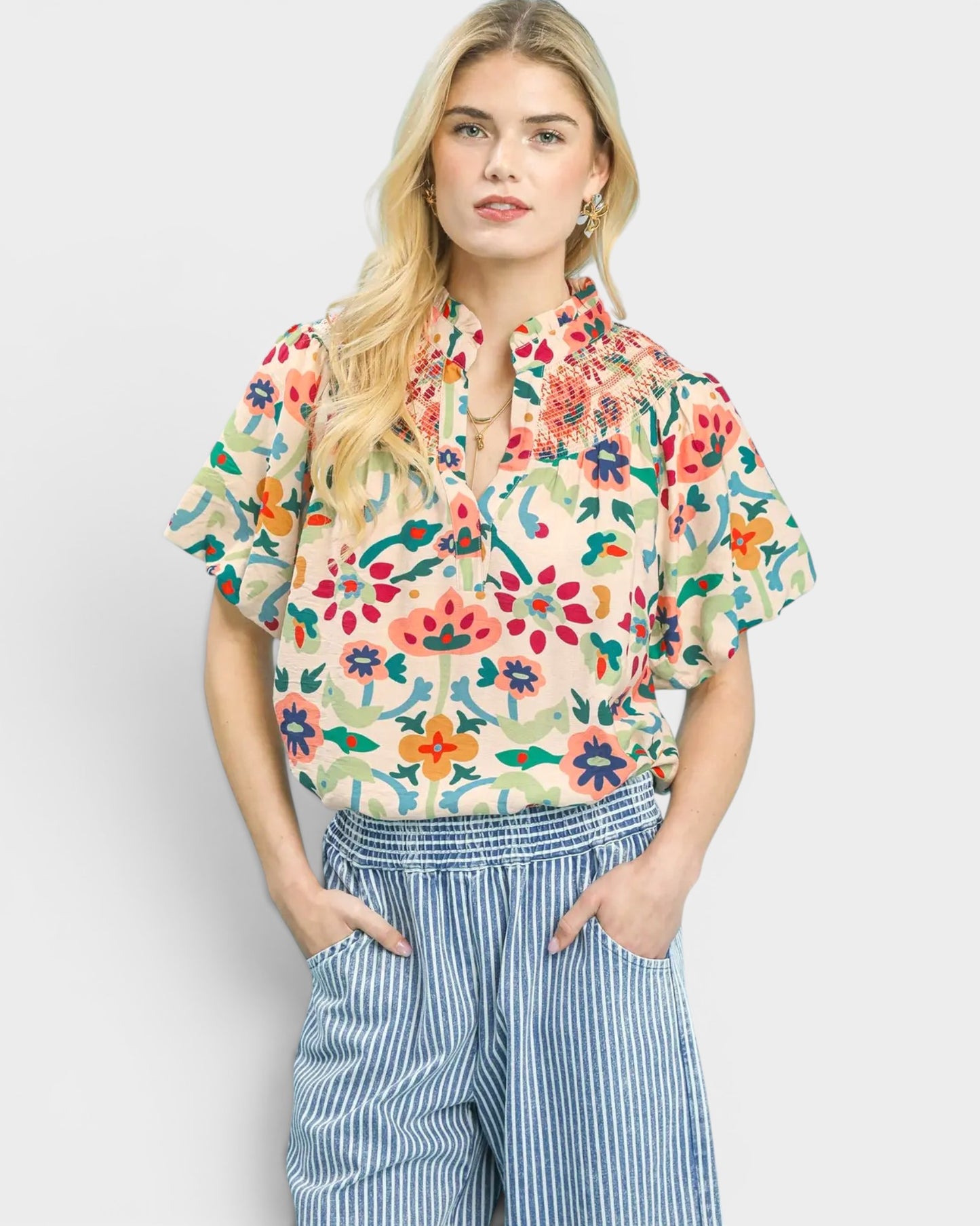 Woman wearing a colorful floral blouse and blue striped pants on a white background