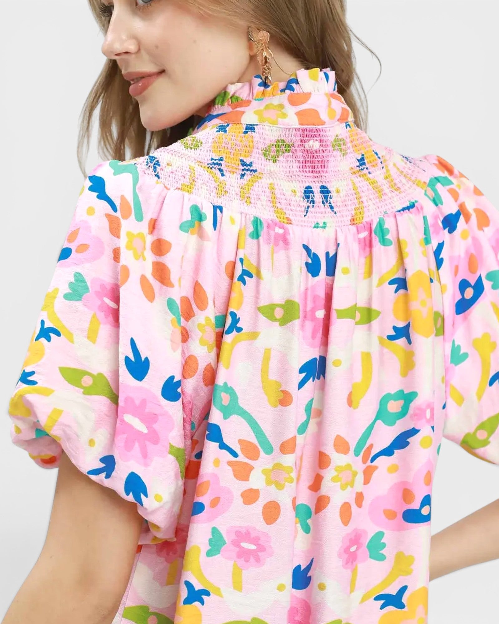 Person wearing a colorful patterned shirt with a plain background