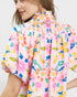 Person wearing a colorful patterned shirt with a plain background