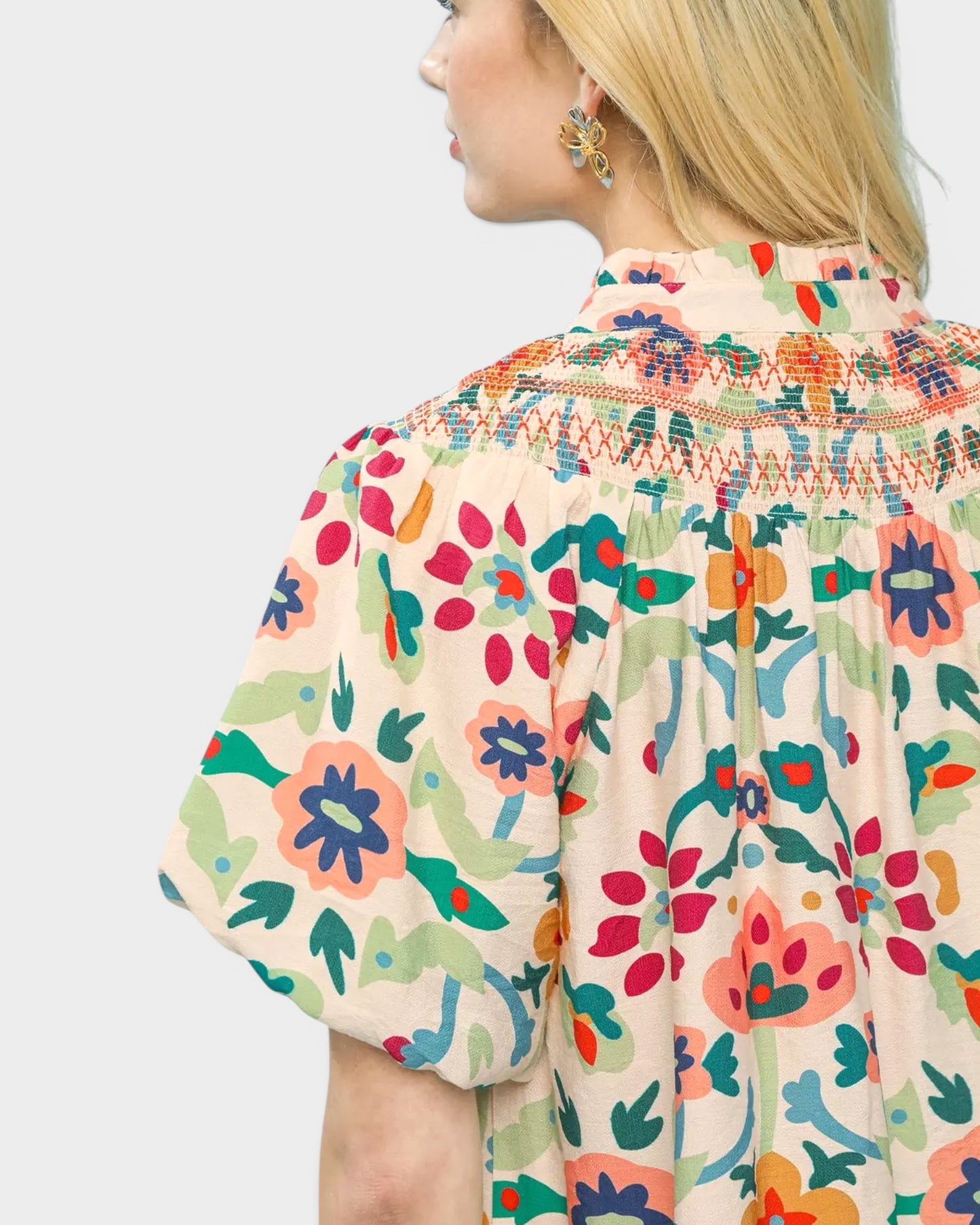 Woman wearing a colorful floral blouse with a plain background