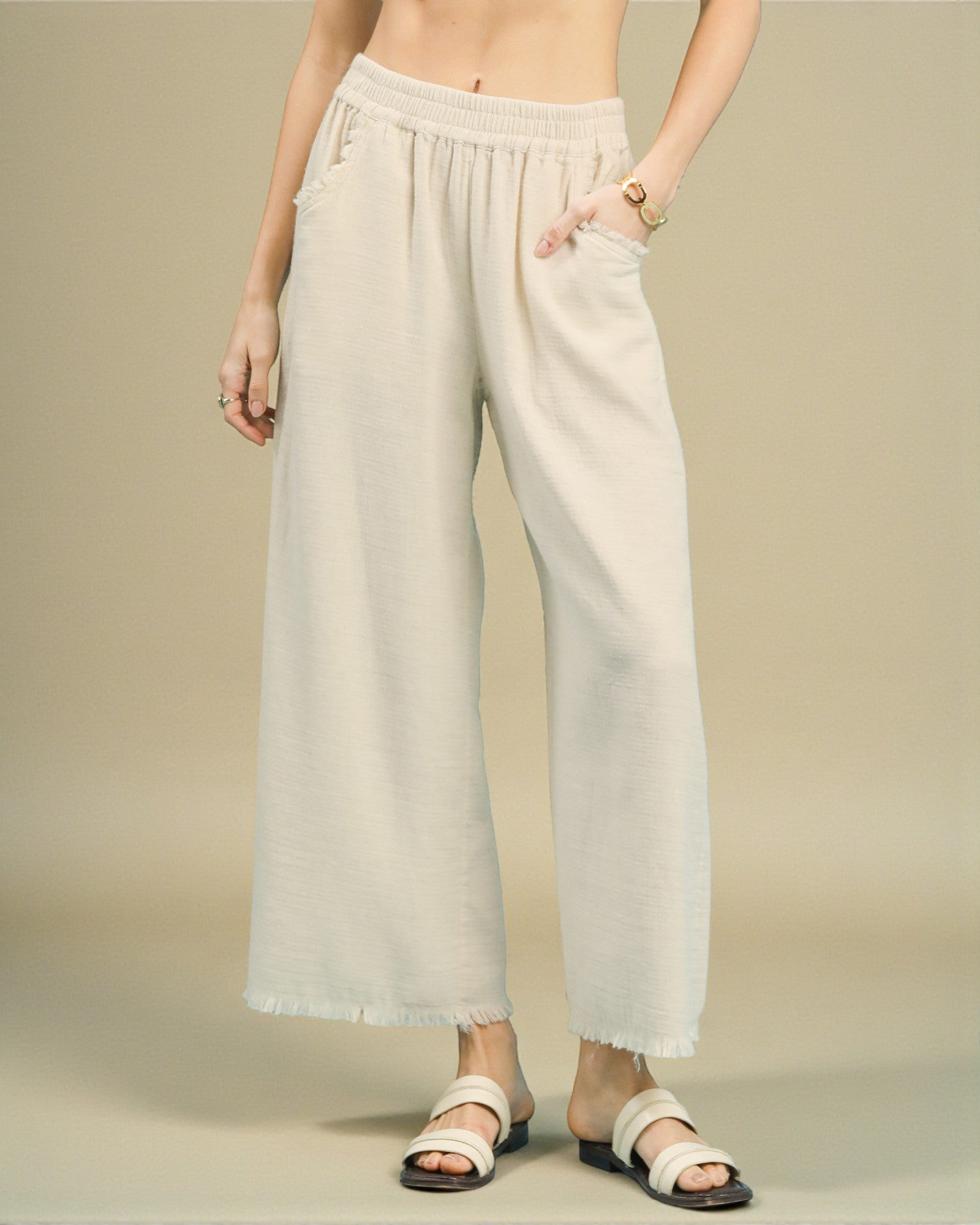 Person wearing light-colored wide-leg pants on a beige background