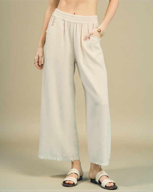 Person wearing light-colored wide-leg pants on a beige background