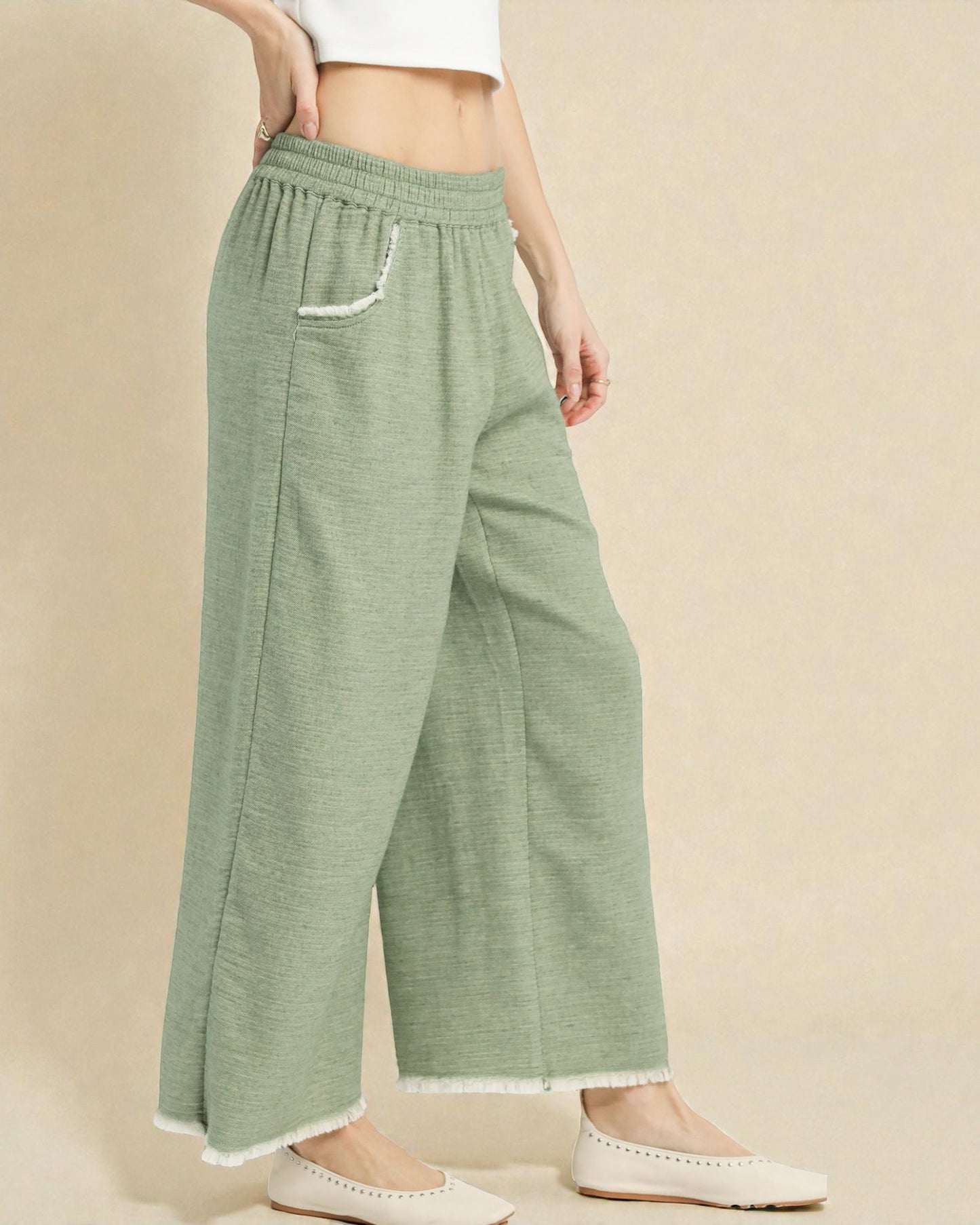 Person wearing green wide-leg pants on a beige background