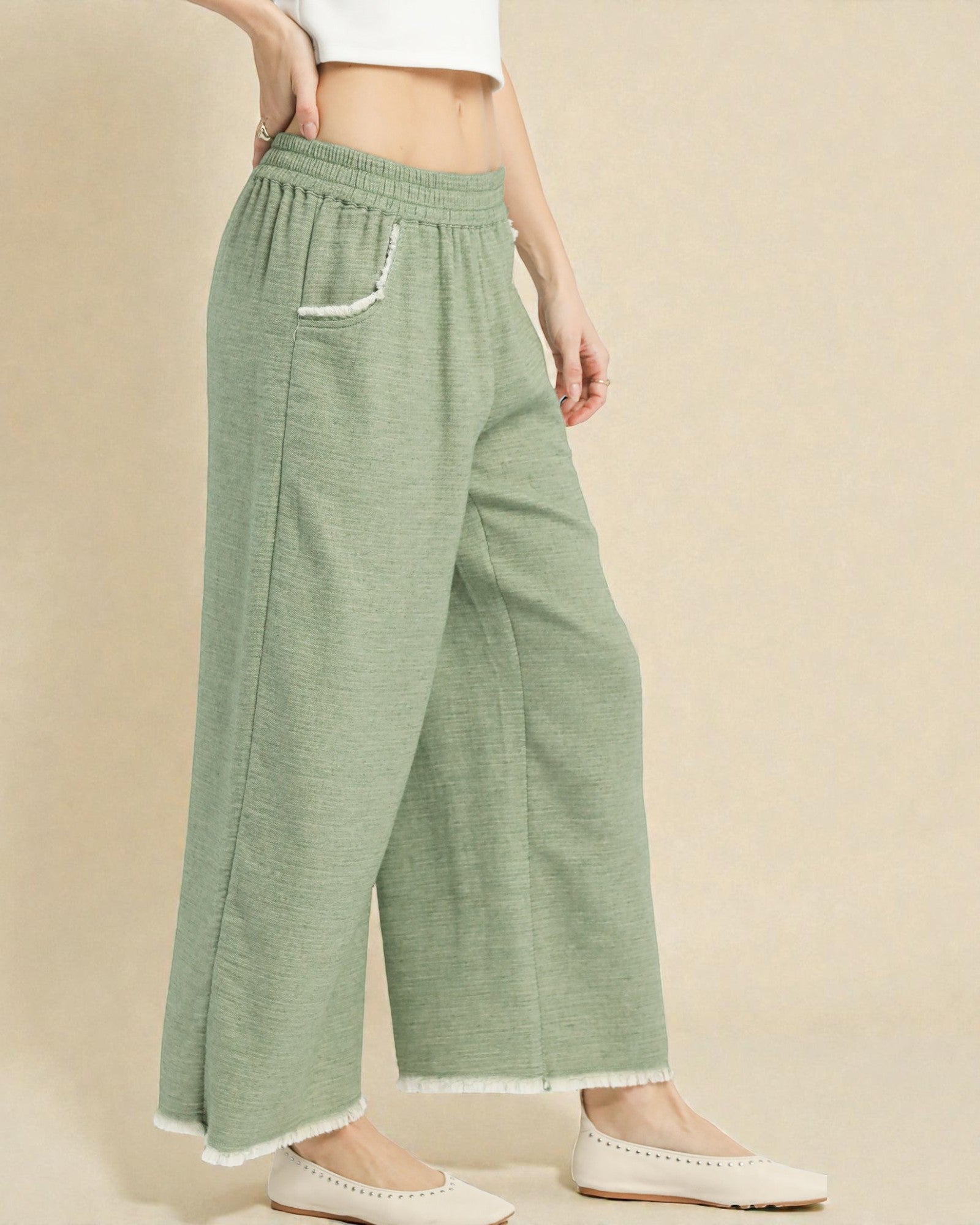 Person wearing green wide-leg pants on a beige background