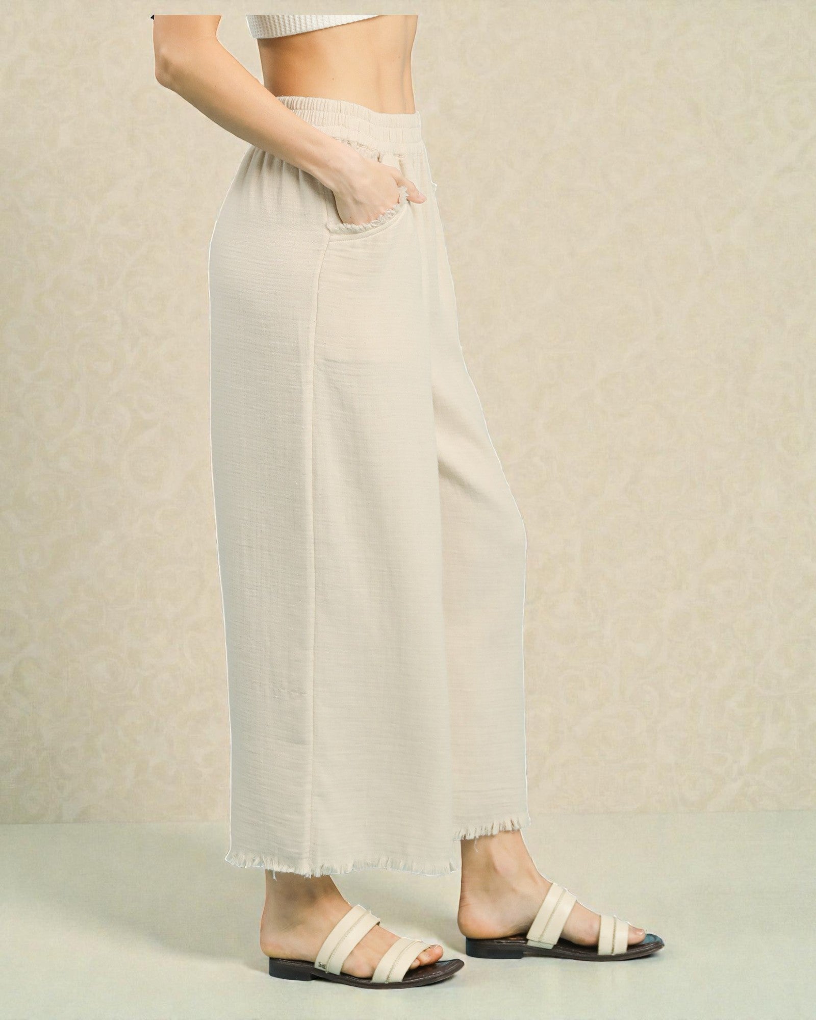 Person wearing light-colored pants and sandals on a neutral background