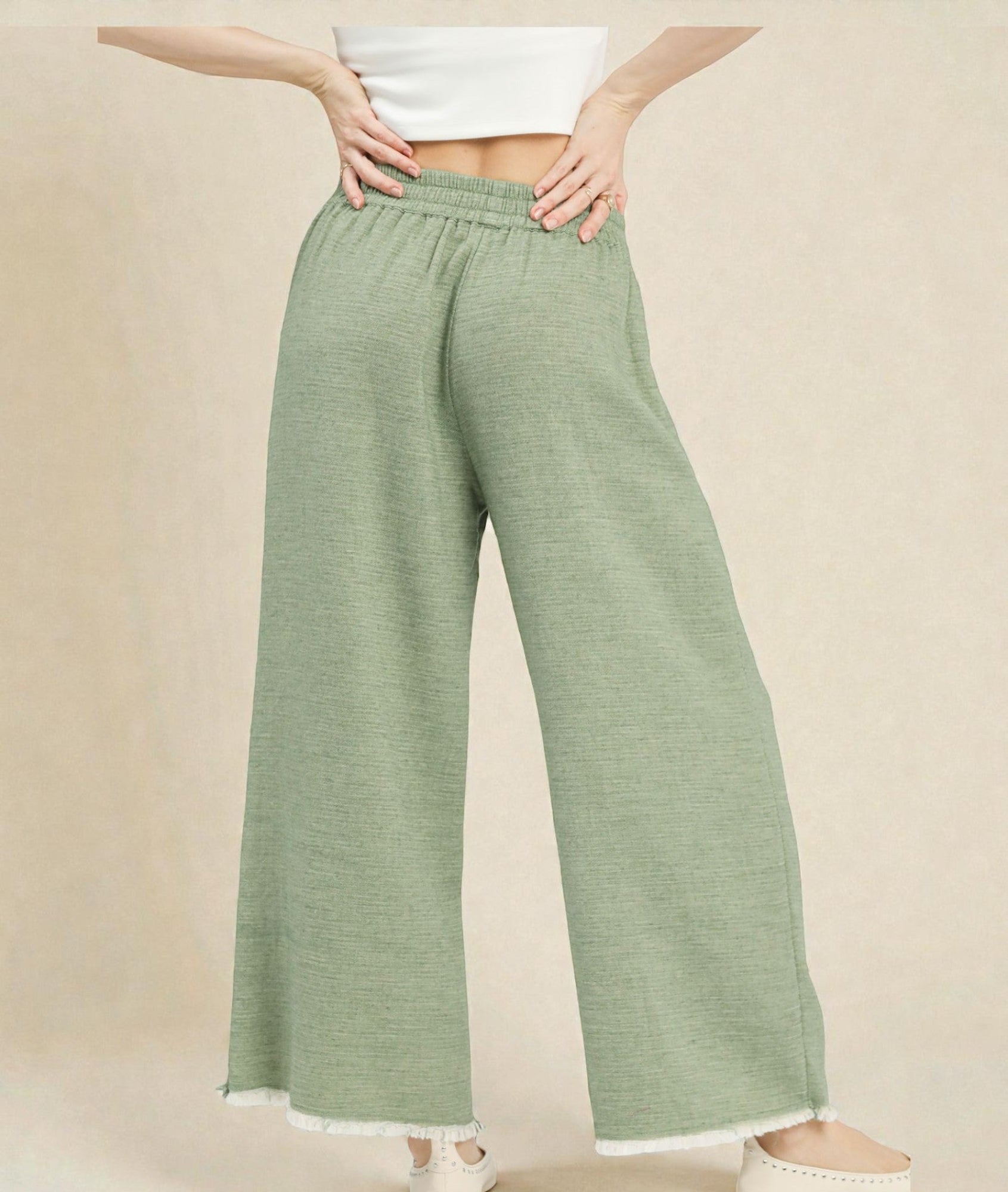 Person wearing green wide-leg pants on a beige background