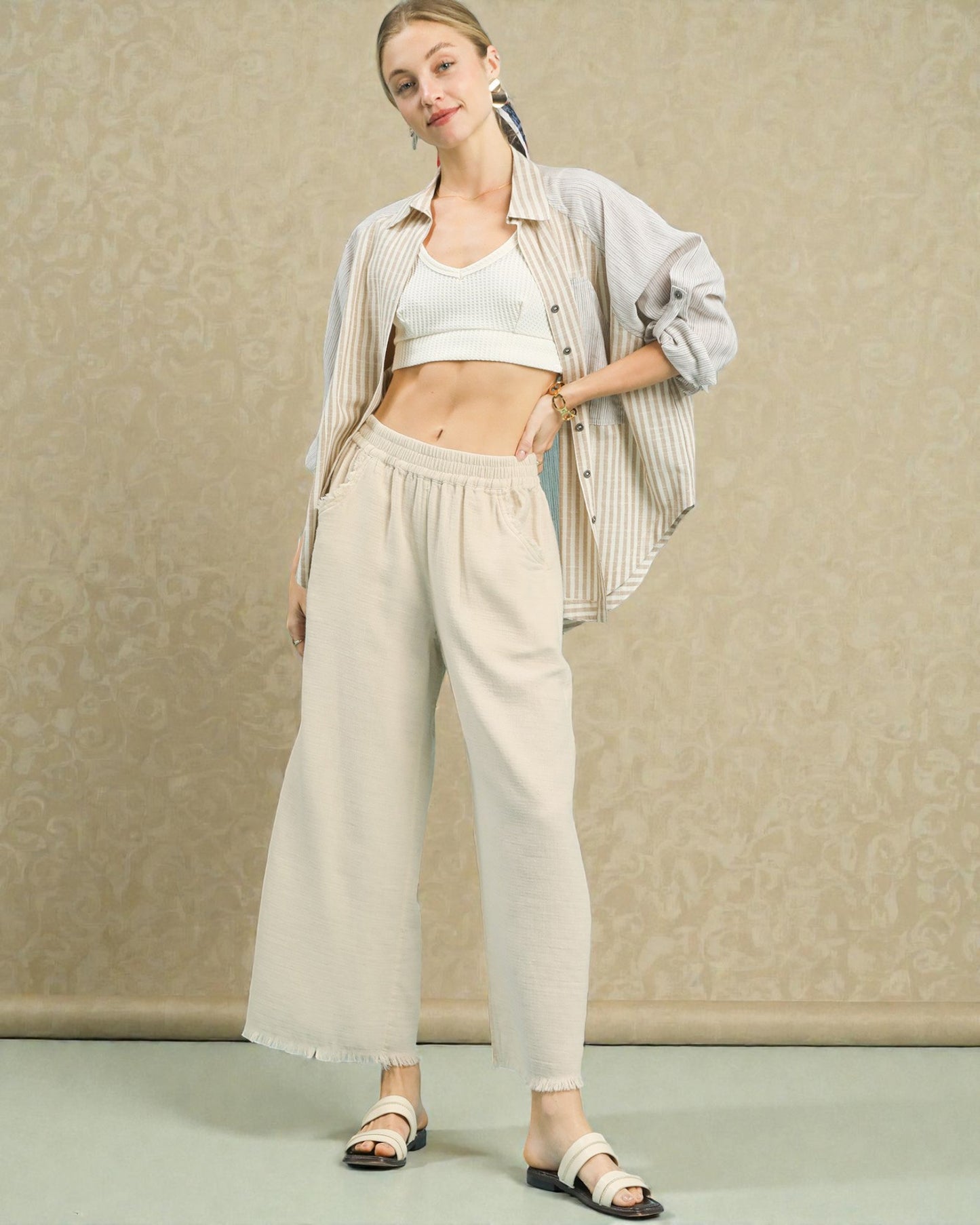 Woman wearing a light-colored outfit with wide-leg pants against a neutral background