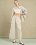 Woman wearing a light-colored outfit with wide-leg pants against a neutral background