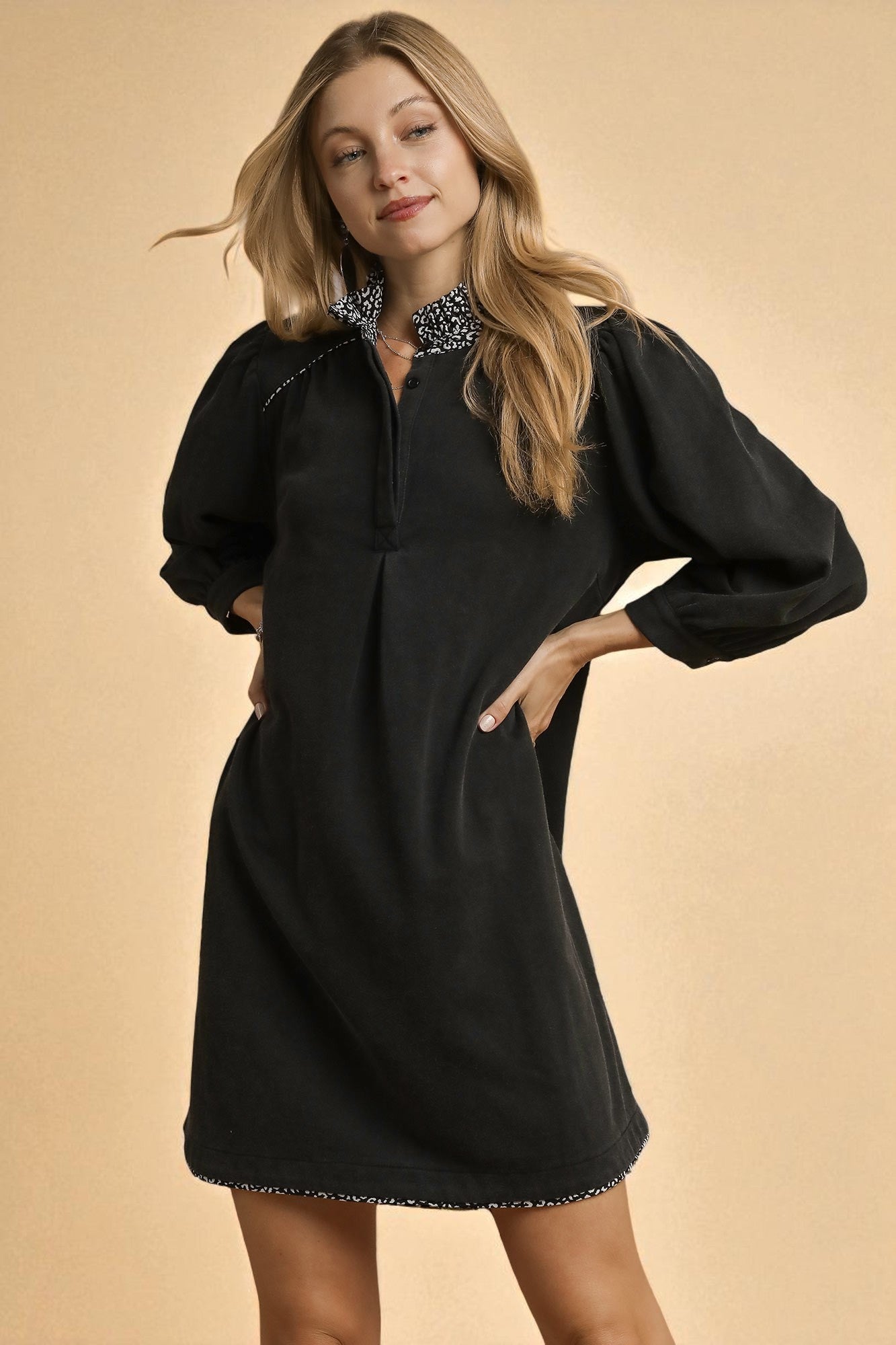 Woman wearing a black dress with long sleeves on a beige background