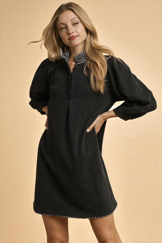 Woman wearing a black dress with long sleeves on a beige background