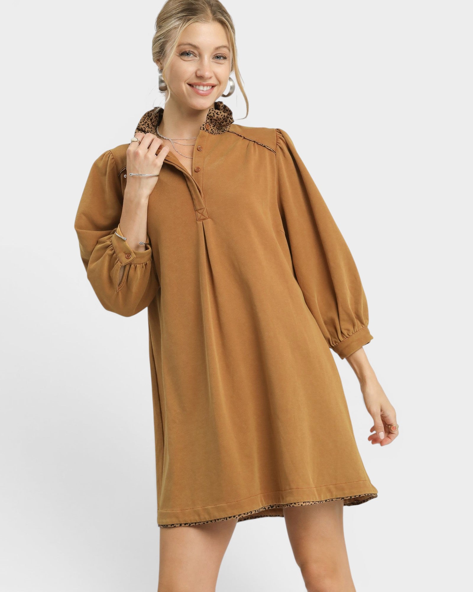 Woman wearing a brown dress with long sleeves on a white background