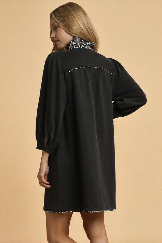 Woman wearing a black dress with intricate detailing on a beige background