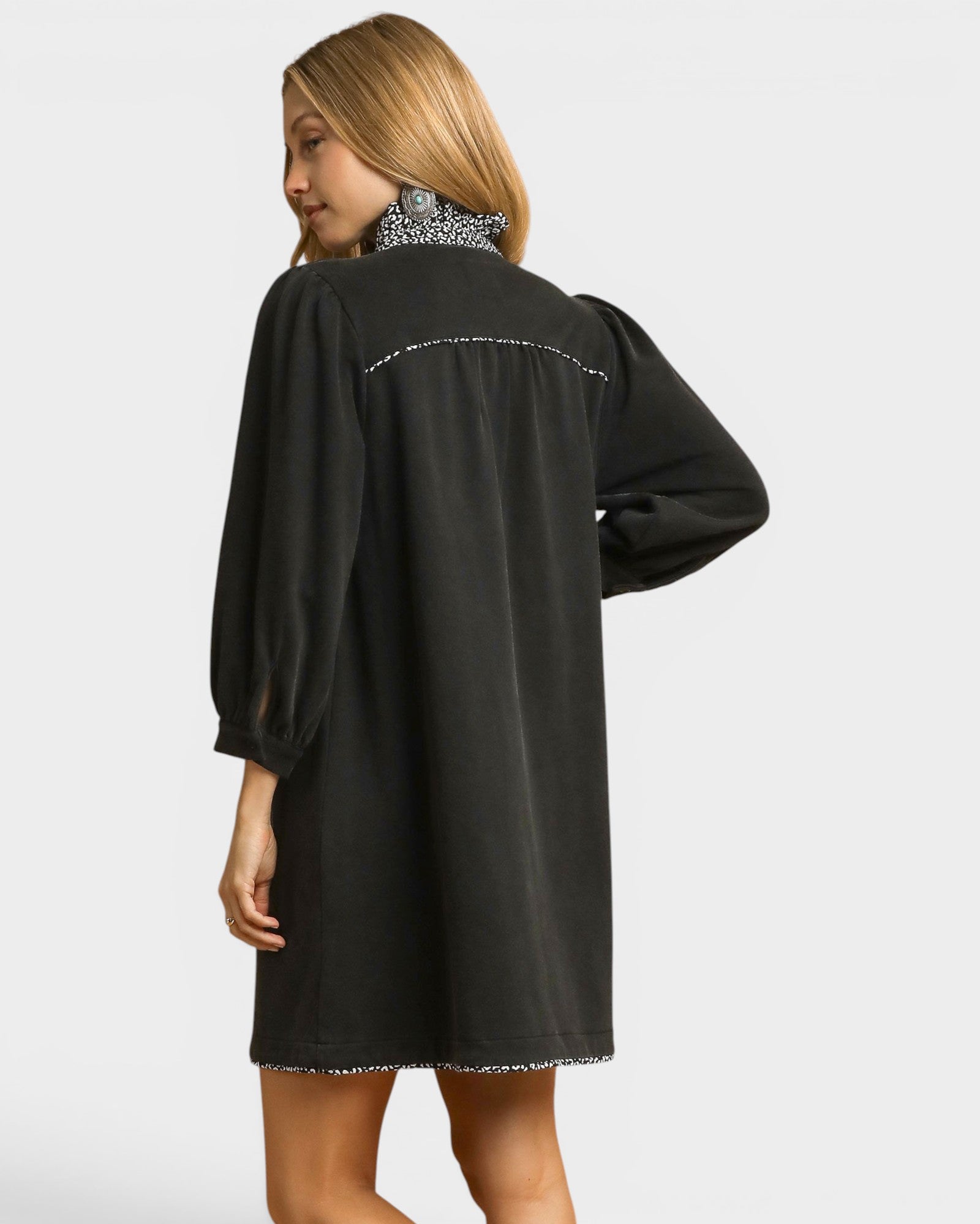 Woman wearing a black dress with long sleeves on a white background