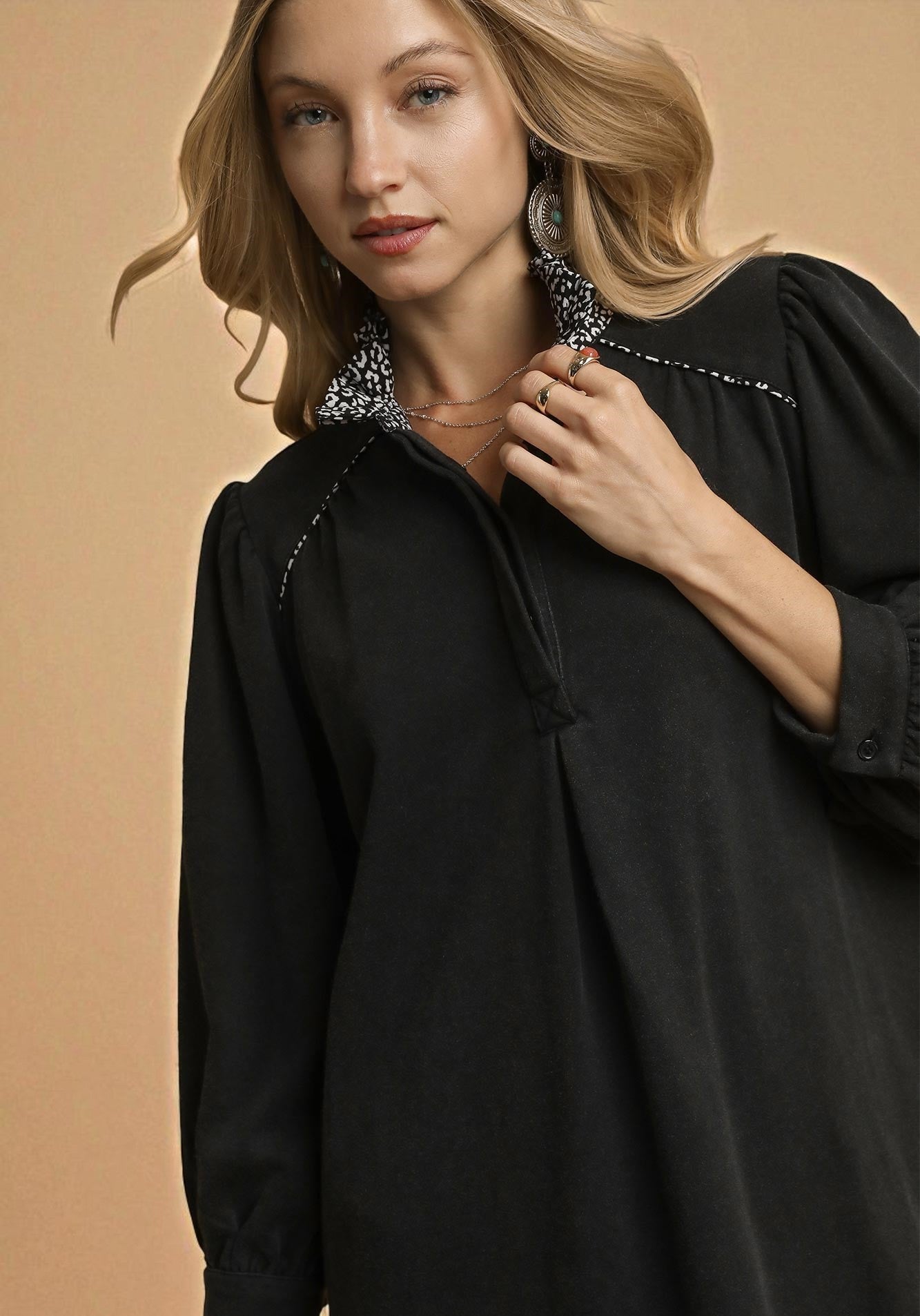 Woman wearing a black blouse with decorative trim against a beige background