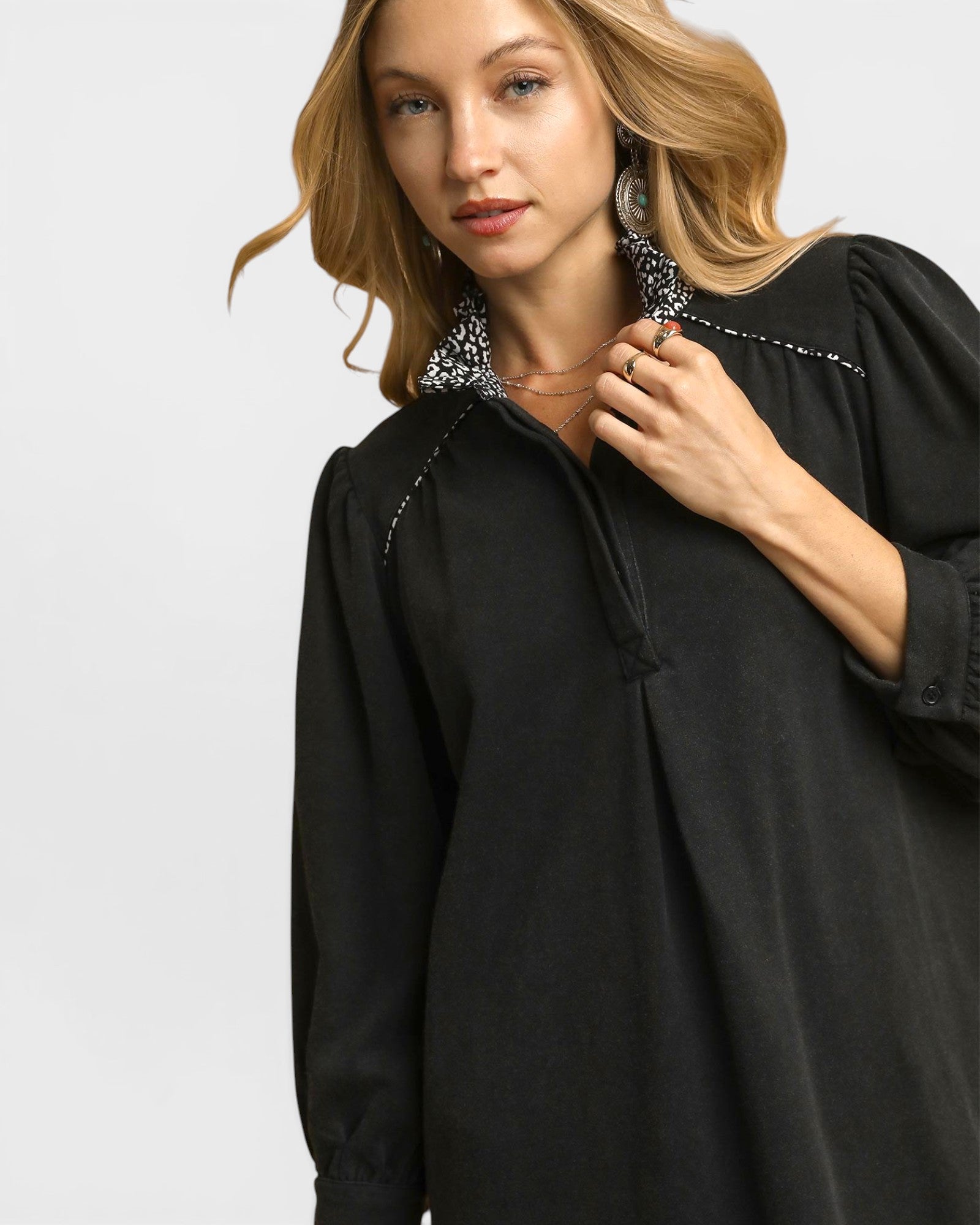 Woman wearing a black dress with decorative collar against a light gray background