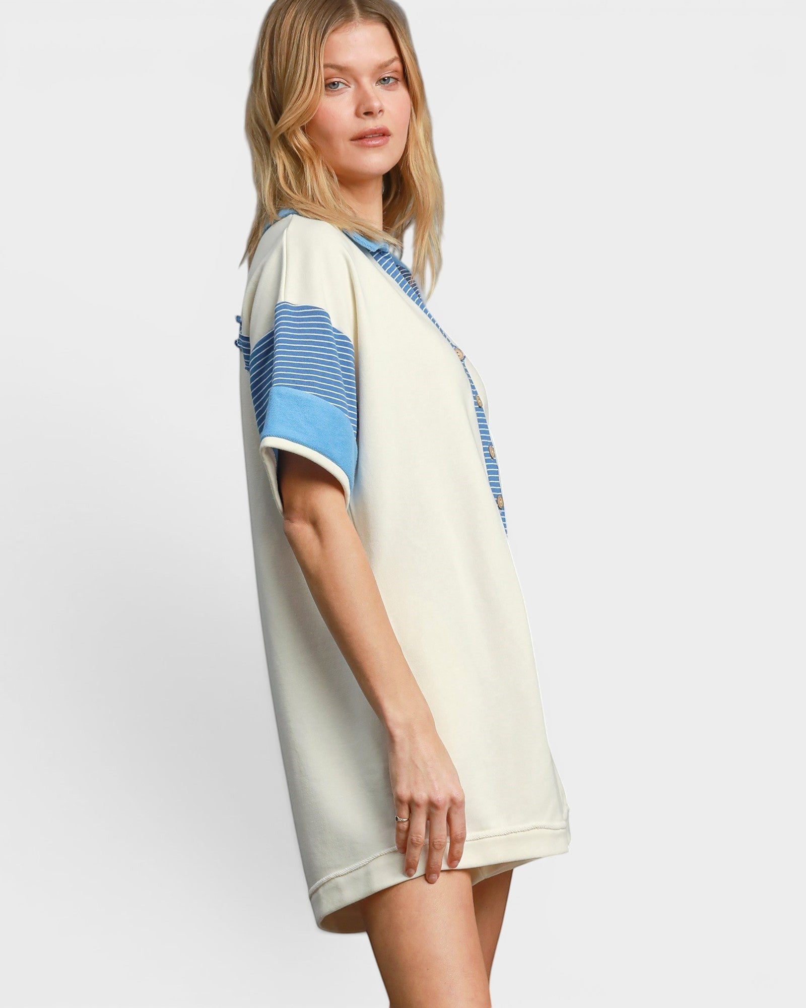 Woman wearing a cream romper with blue accents on a white background