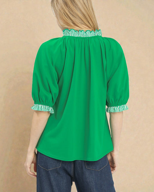 Green blouse with smocked details on a beige background