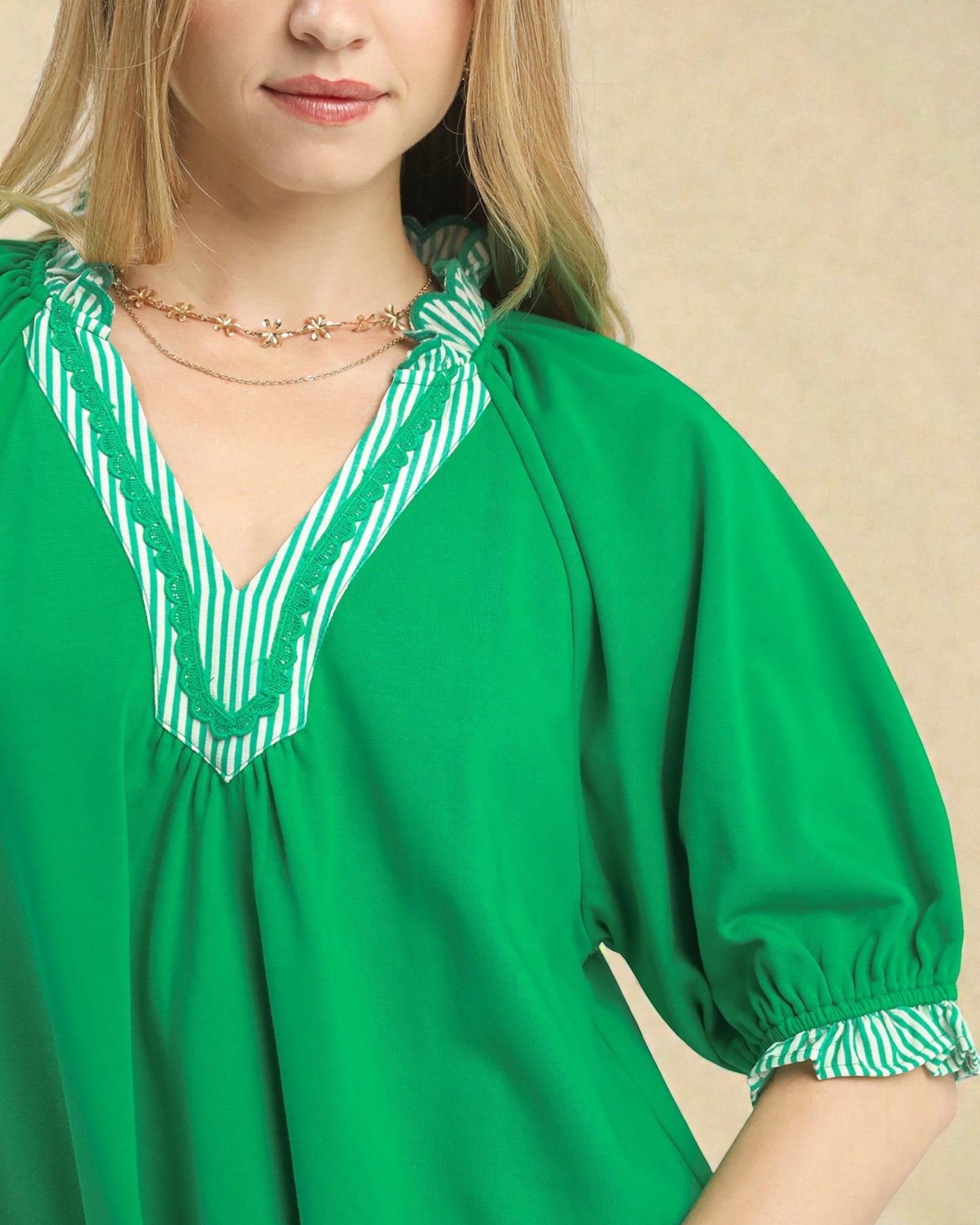 Green dress with white striped neckline and cuffs worn by a person.