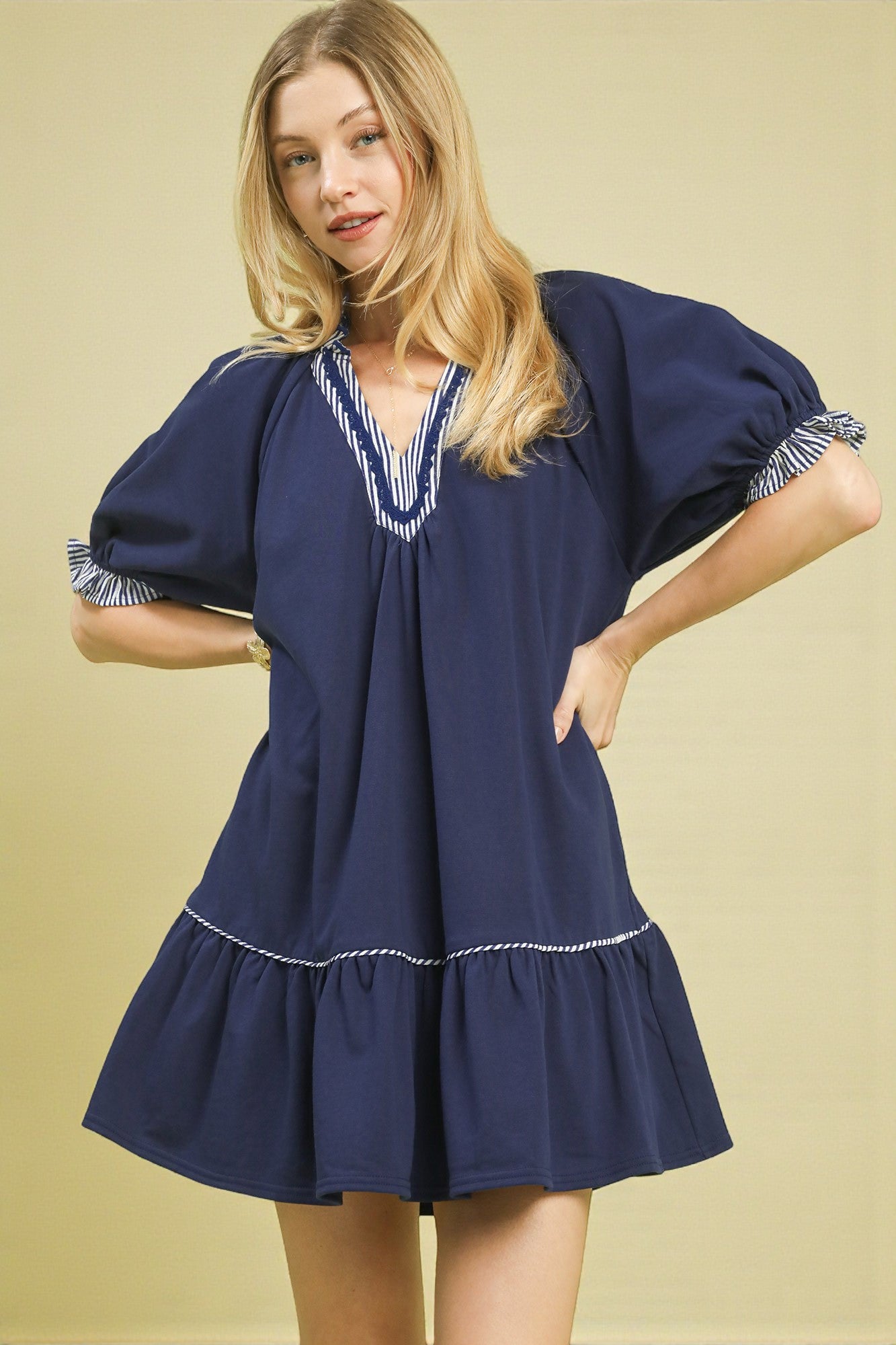 Woman wearing a navy blue dress with white trim on a beige background