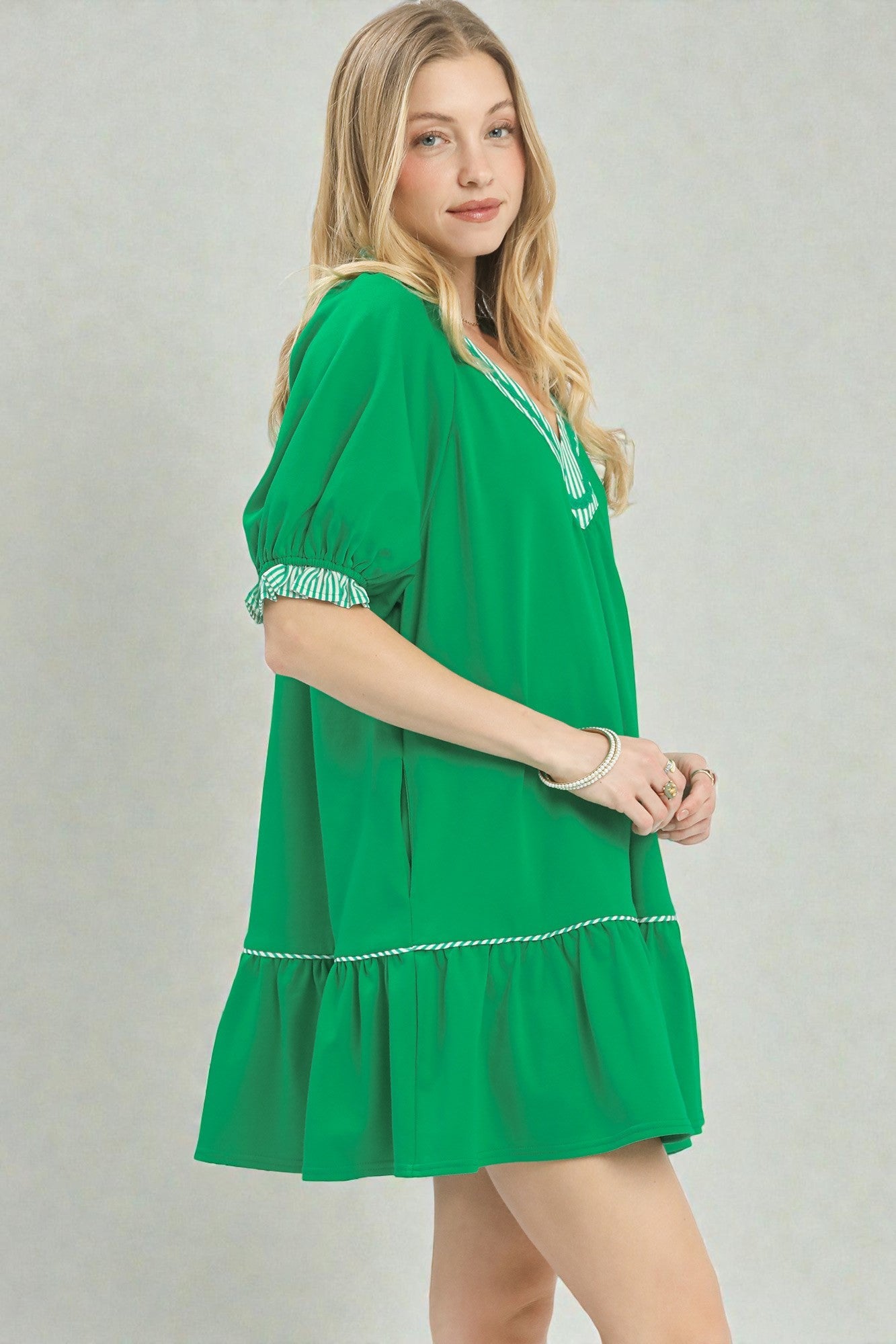 Woman wearing a green dress with white trim on a plain background