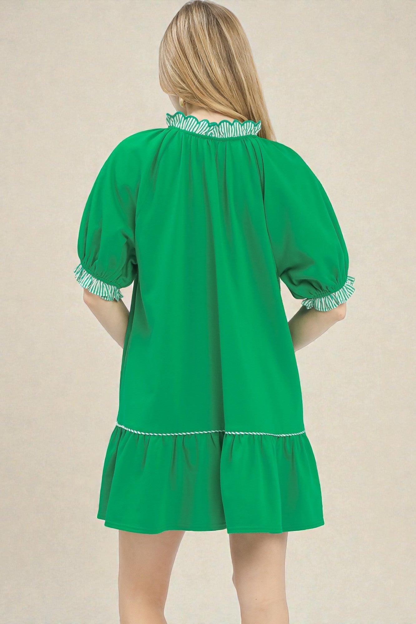 Green dress with white trim on a beige background