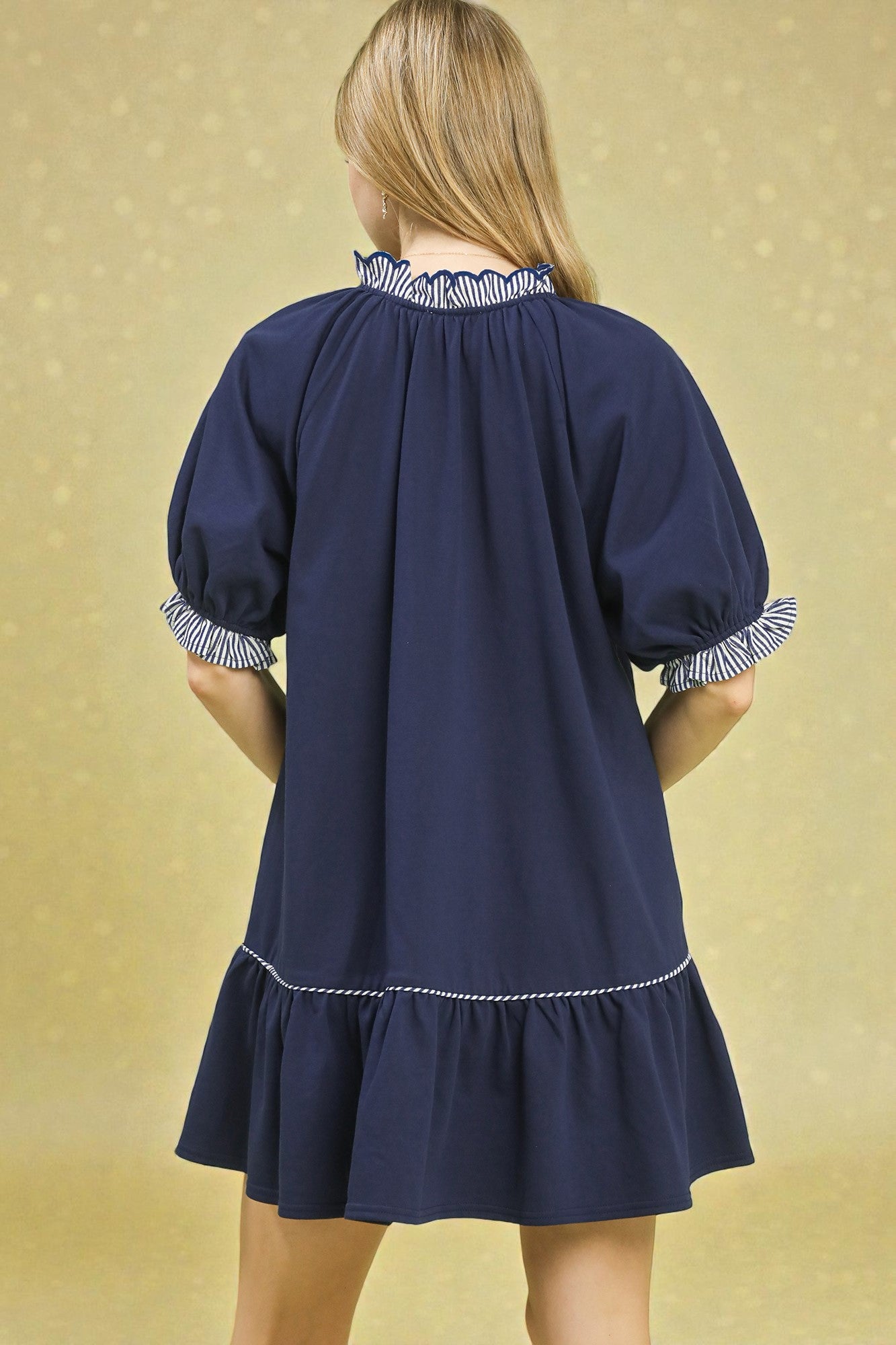 Navy blue dress with white trim on a gold background