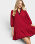 Woman wearing a red dress with black trim on a white background