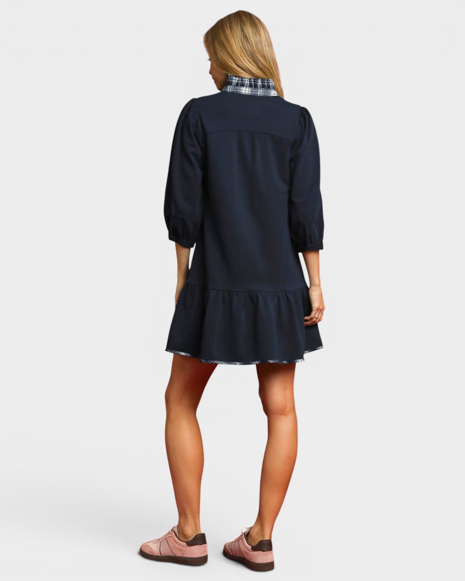 Woman wearing a navy dress with plaid collar on a white background