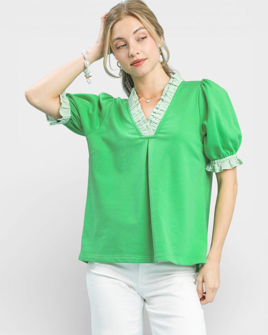 Woman wearing a green blouse with lace details on a white background