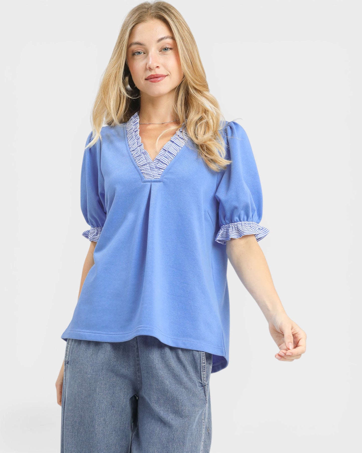 Woman wearing a blue blouse with ruffled details on a white background