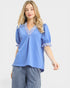 Woman wearing a blue blouse with ruffled details on a white background