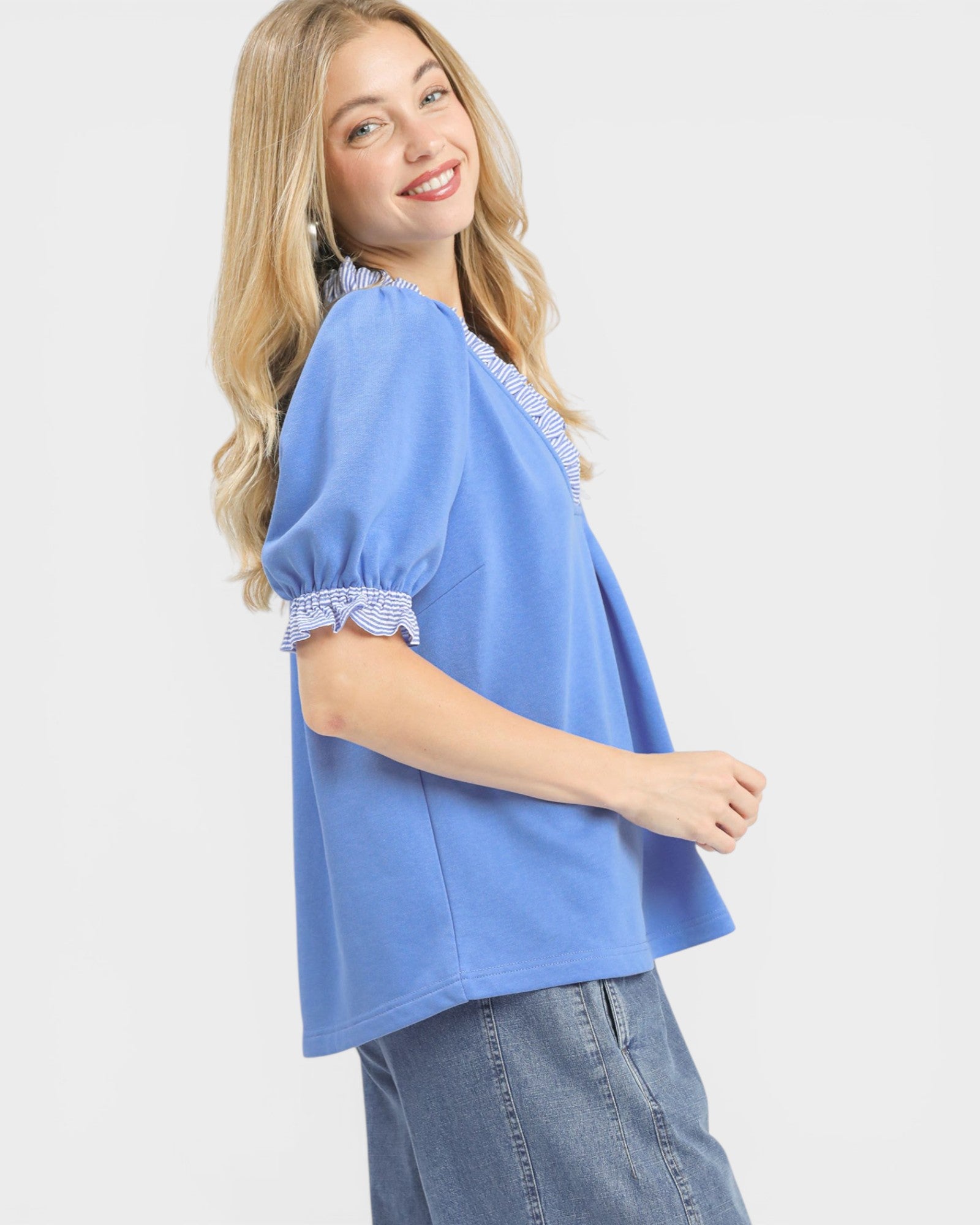 Woman wearing a blue top with lace trim on a white background