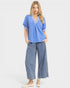 Woman wearing a blue top and denim pants on a white background